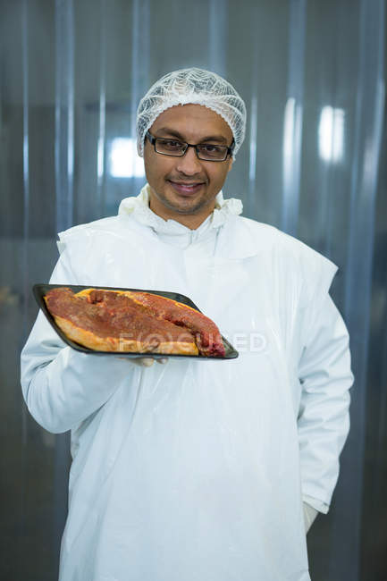 Retrato de açougueiro segurando bandeja de carne na fábrica de carne — Fotografia de Stock