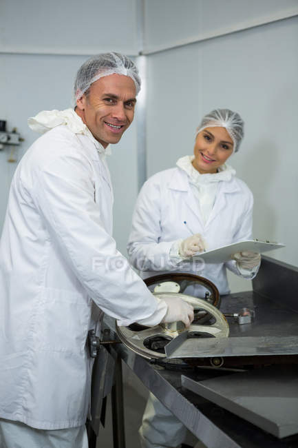 Portrait of butchers maintaining record on clipboard at meat factory — Stock Photo