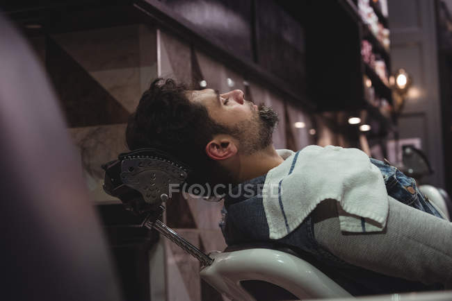 Mann entspannt sich auf Stuhl im Friseurladen — Stockfoto