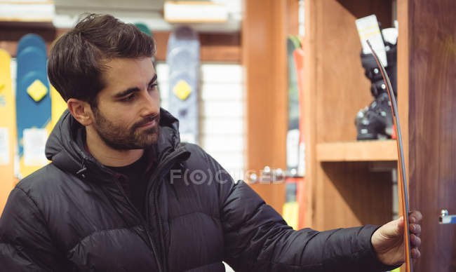 Hombre guapo seleccionando esquí en una tienda - foto de stock