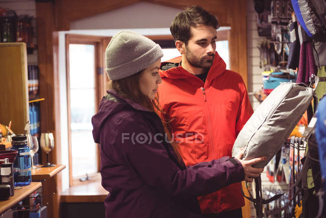 Casal selecionando mochila juntos em uma loja — Fotografia de Stock