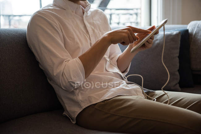 A meio da seção do homem ouvindo música no tablet digital em casa — Fotografia de Stock