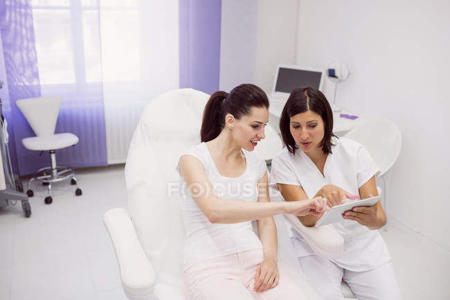 Лікар і пацієнтка обговорюють цифровий планшет у клініці — стокове фото