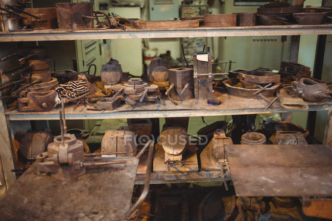 Moldes de metal para sopro de vidro dispostos na prateleira na fábrica de sopro de vidro — Fotografia de Stock