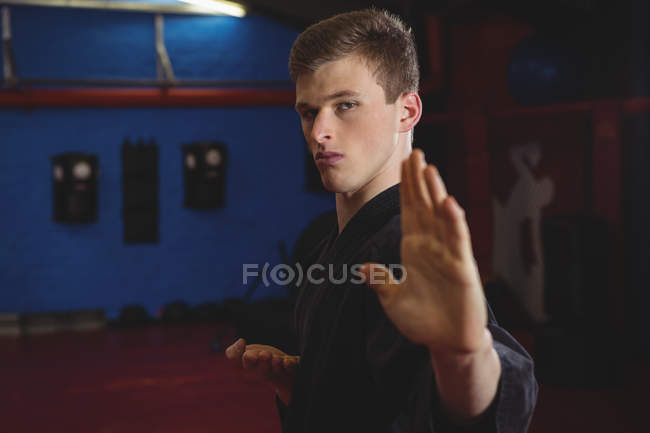 Молодий дорослий карате гравець виконує позицію карате в фітнес-студії — стокове фото