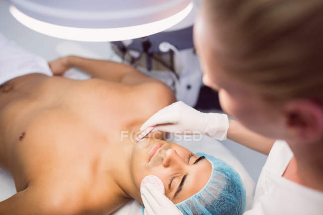Arzt reinigt Gesicht des Patienten mit Gesichtsschwämmen in Klinik — Stockfoto