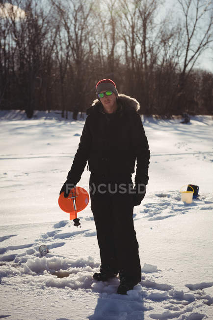 Mid adult ice fisherman holding spinning reel in snowy landscape — Stock Photo