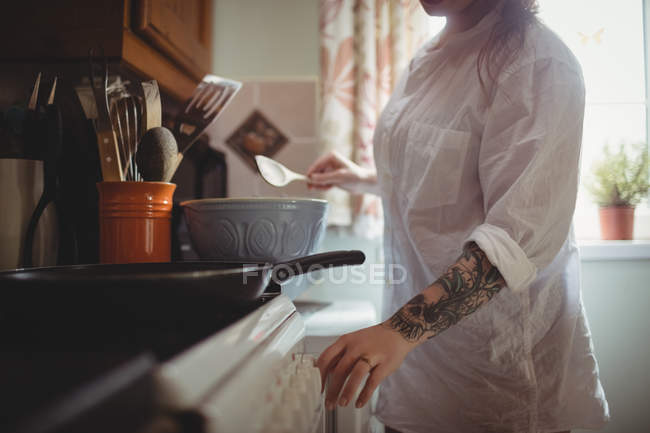 Parte média da mulher de pé e preparando a refeição na cozinha em casa — Fotografia de Stock