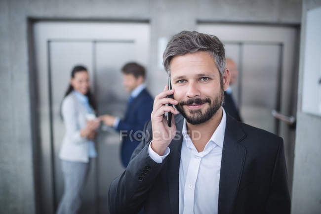 Бизнесмен разговаривает по мобильному телефону в офисе — стоковое фото