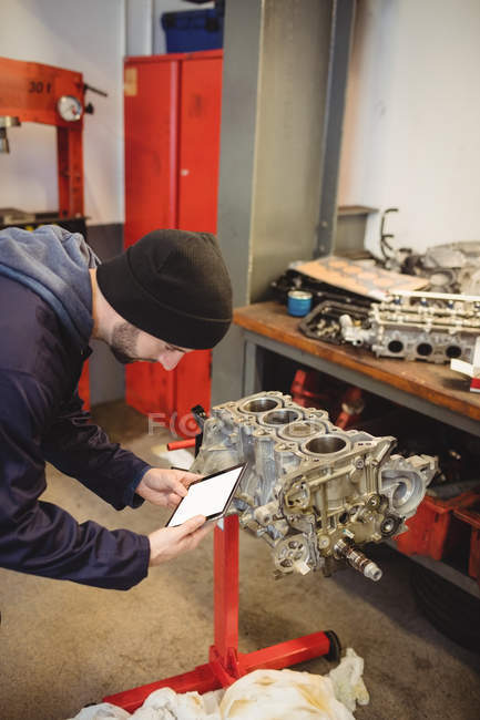 Mechanic using digital tablet on car parts in repair garage — Stock Photo