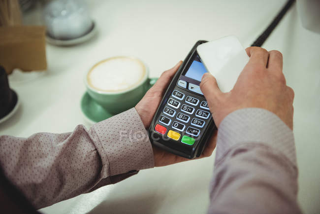 Gros plan des mains effectuant le paiement par téléphone mobile grâce à la technologie NFC — Photo de stock