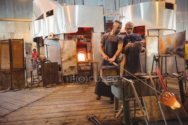 Команда скляних дзвонів, що використовують цифрові при роботі над розплавленим склом на заводі зі скляних дзеркал — стокове фото