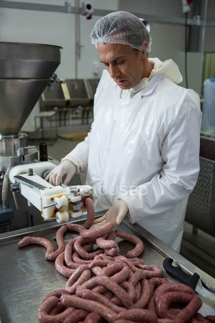 Male butcher processing sausages at meat factory — Stock Photo