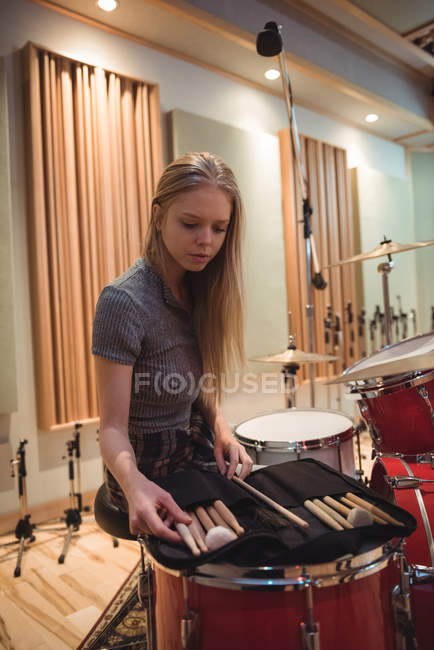Donna guardando bacchette di batteria in studio di registrazione — Foto stock