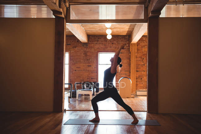 Mujer practicando yoga en gimnasio, vista lateral - foto de stock
