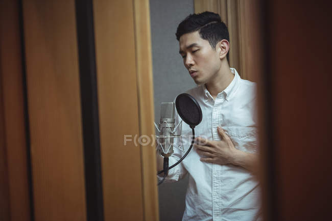 Homme chantant sur microphone en studio d'enregistrement — Photo de stock