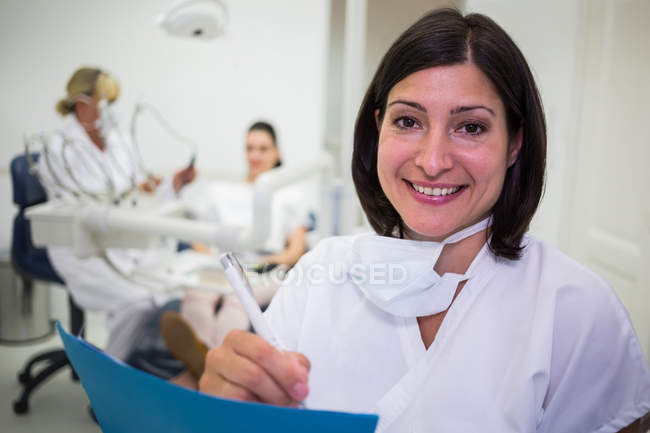 Портрет жінки-стоматолога, що пише звіт у стоматологічній клініці — стокове фото