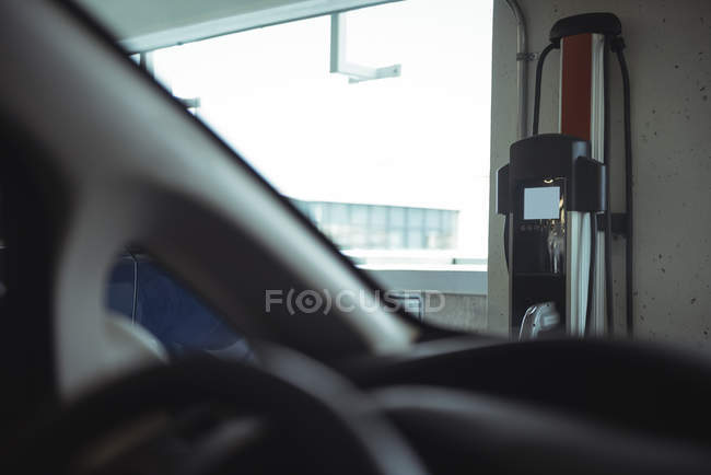 Macchina elettrica a innesto vista attraverso il parabrezza dell'auto presso la stazione di ricarica del veicolo elettrico — Foto stock