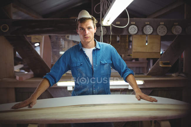 Vista frontal del hombre haciendo tabla de surf en taller - foto de stock