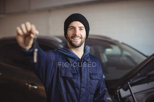 Portrait of mechanic in garage holding car key — Stock Photo