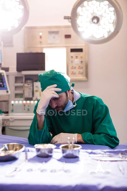 Напряженный хирург сидит в операционной в больнице — стоковое фото