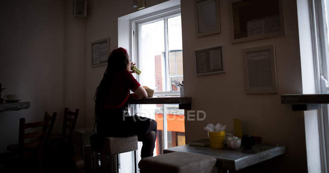 Вид ззаду жінки, що п'є медичний напій у кафе — стокове фото