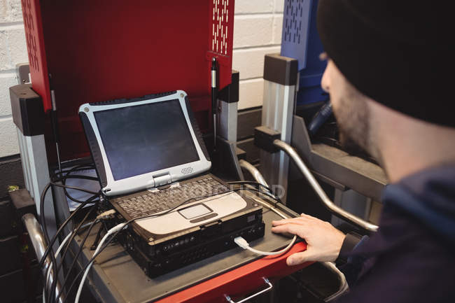 Механик с помощью ноутбука в ремонтном гараже — стоковое фото
