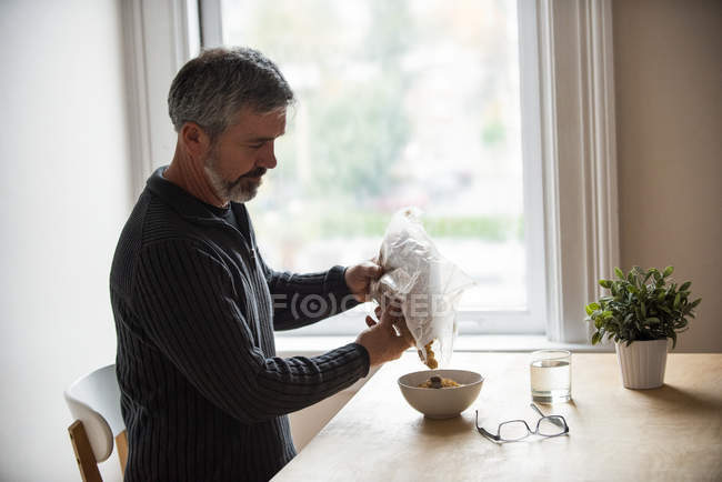 Чоловік вливає зернові в миску в домашніх умовах — стокове фото