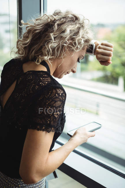 Femme d'affaires énervée en utilisant le téléphone mobile dans le bureau — Photo de stock