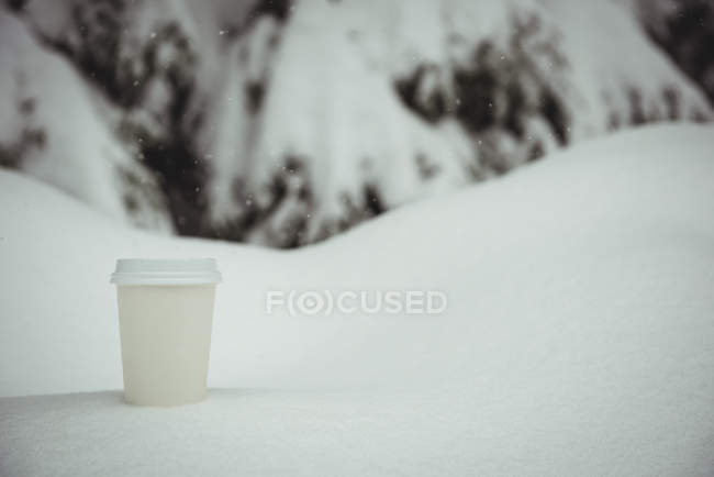 Einweg-Kaffeetasse im Winter in einer verschneiten Landschaft — Stockfoto