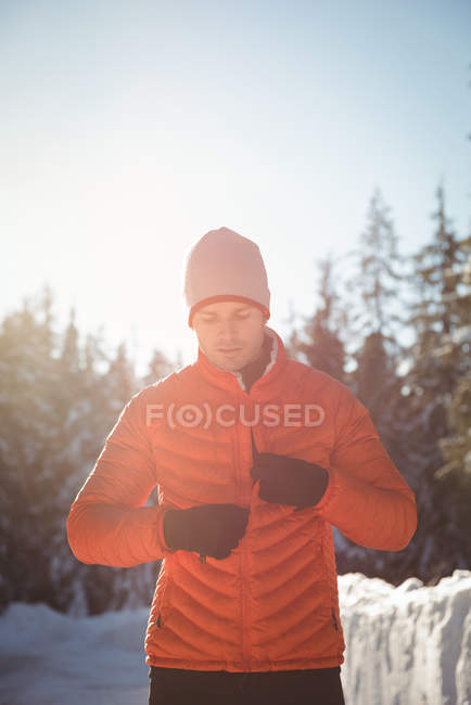Man removing warm clothing in forest during winter — Stock Photo