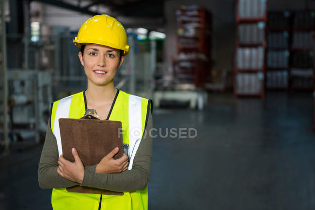 Retrato de una trabajadora segura sosteniendo el portapapeles en el almacén - foto de stock