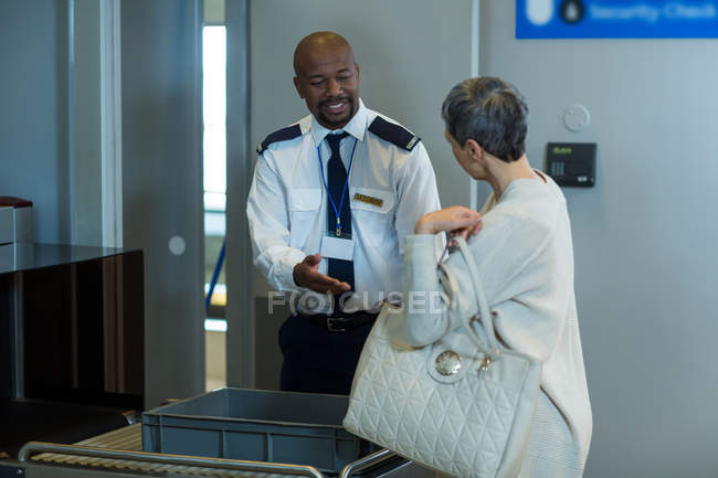Commuter getting a bag checked from airport security officer in airport terminal — Stock Photo