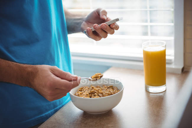 Mittelteil des Mannes mit Handy beim Frühstück in der heimischen Küche — Stockfoto