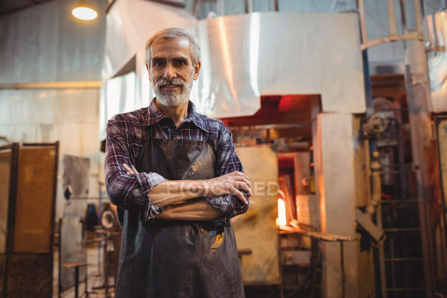 Portrait of glassblower standing with arms crossed at glassblowing factory — Stock Photo