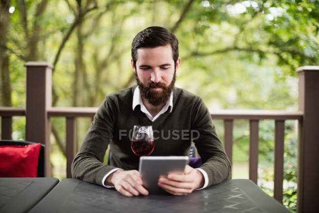 Homme utilisant tablette numérique tout en ayant un verre de vin dans le bar — Photo de stock