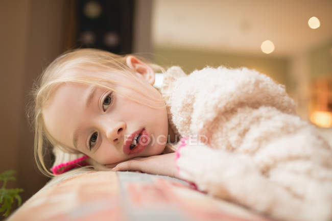 Portrait of cute girl lying on sofa in living room at home — Stock Photo