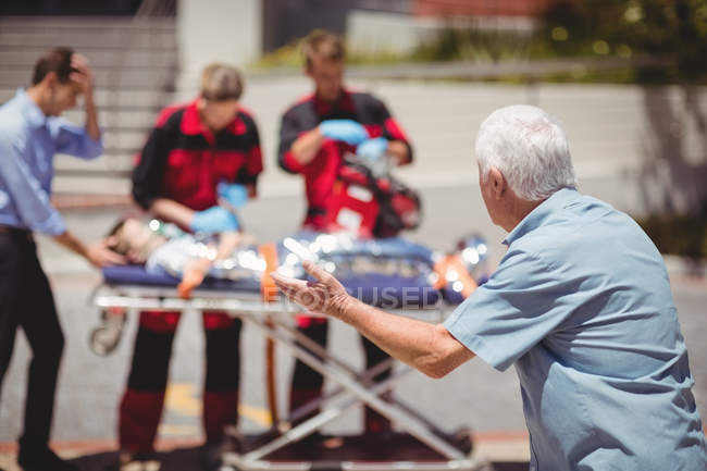 Los paramédicos examinan a un chico herido en la calle - foto de stock
