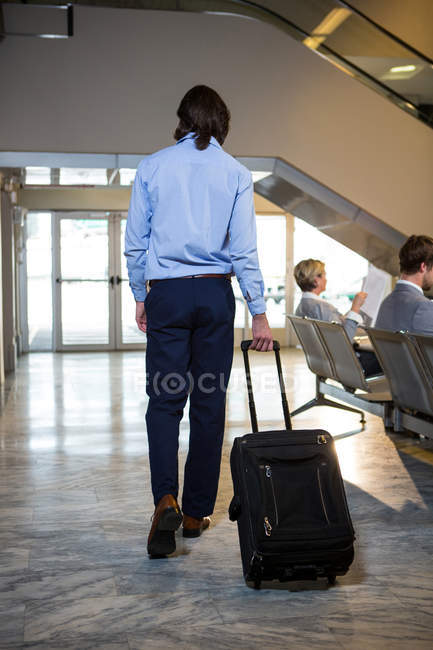 Pasajero caminando con equipaje en la sala de espera en el aeropuerto - foto de stock