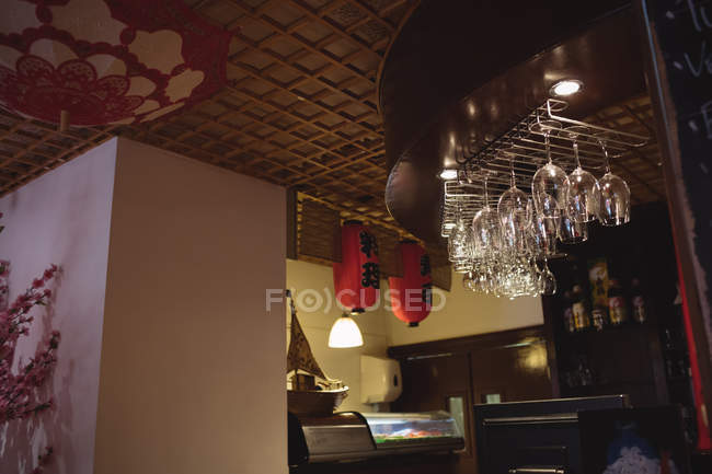 Copas de vino colgando en el mostrador del bar en restaurante - foto de stock