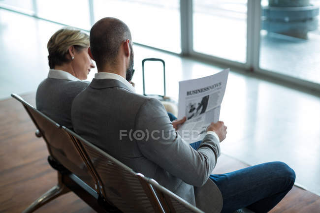 Empresários lendo jornal na área de espera no terminal do aeroporto — Fotografia de Stock