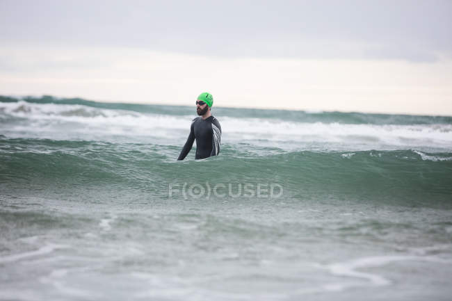 Atleta in muta in piedi in acqua di mare — Foto stock