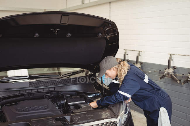 Mecánica femenina servicio de coches en el garaje de reparación - foto de stock