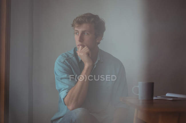 Hombre reflexivo sentado escritorio en casa - foto de stock