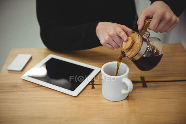 A meio da seção de homem derramando café de chaleira de café na caneca no café — Fotografia de Stock