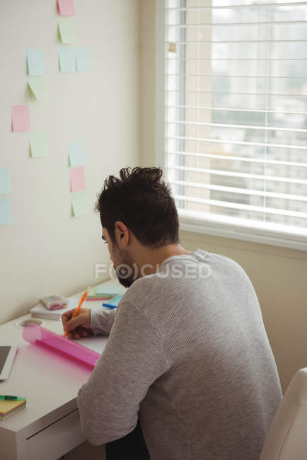 Attentive man writing on document while sitting at desk — Stock Photo