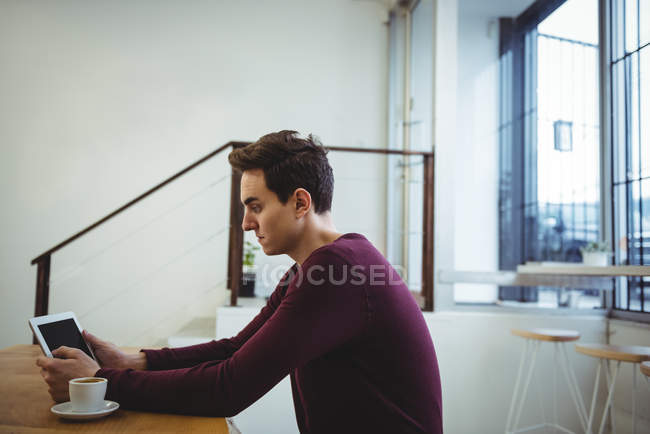 Homem usando tablet digital enquanto sentado em uma cafeteria — Fotografia de Stock