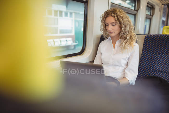 Mulher de negócios adulta média usando laptop enquanto viaja de trem — Fotografia de Stock