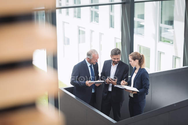 Группа деловых людей, обсуждающих у лестницы в офисе — стоковое фото