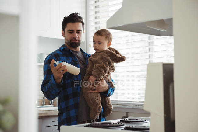 Pai preparando leite para seu bebê na cozinha em casa — Fotografia de Stock